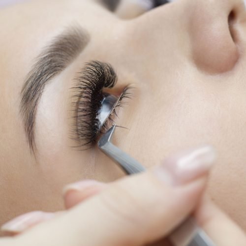 Extension of the lower eyelashes. a young woman undergoes a close-up eyelash extension procedure. Tweezers. Down below